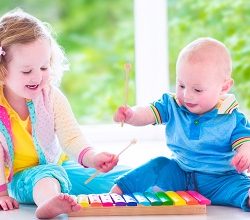 Big sister and baby brother playing with xylophone