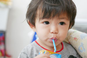 child drinking from carton with plastic straw