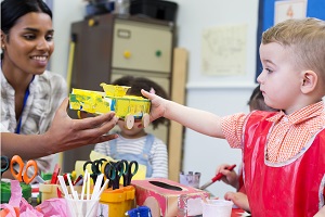 child handing practioner junk model at craft time