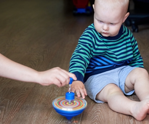 child playing with spinning top on the floor