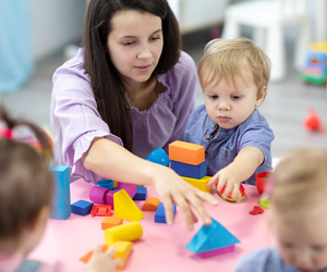 child and practitioner playing with coloured blocks at a table