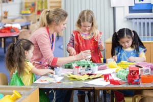 practitioner crafting with three children in aprons