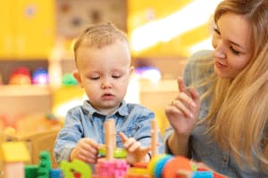 practitioner watching child play with wooden toys