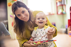 practitioner with baby on knee looking to camera