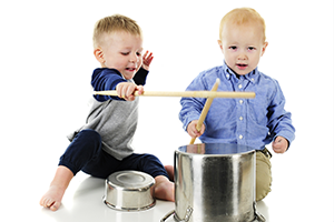 two boys banging on pans with drumsticks