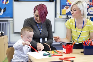 two practitioners in lanyards watching child play
