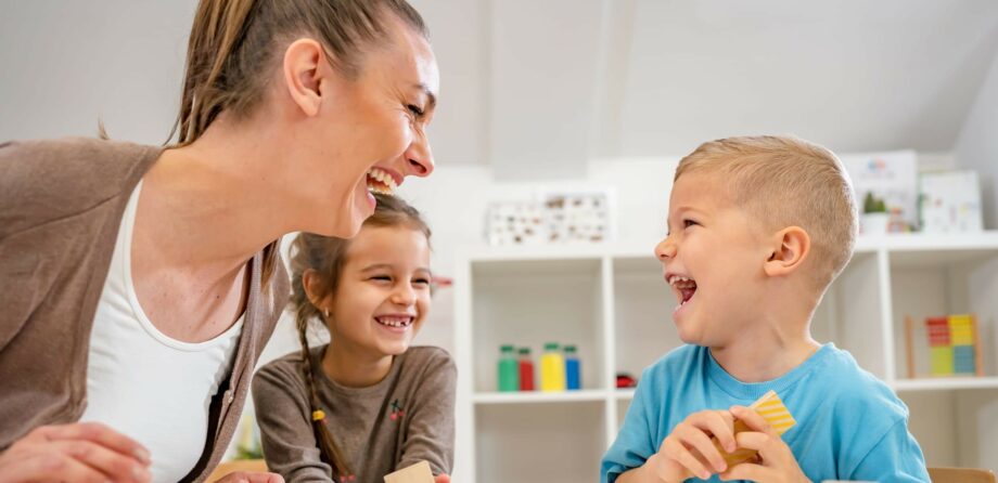 positive behaviour - children laughing at nursery with practitioner