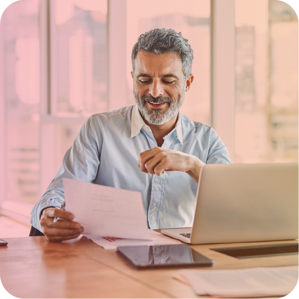 Man sat at desk in front of laptop reading a document